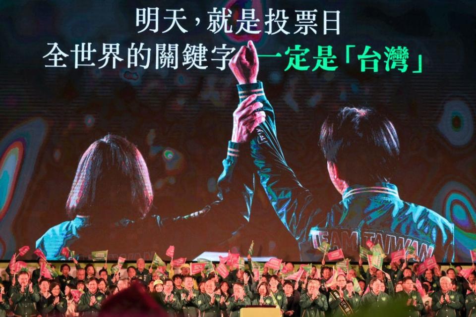 Taiwan President Tsai Ing-wen (C), waves in front of a giant screen showing Lai Ching-te, presidential candidate for 2024 from the ruling Democratic Progressive Party (DPP), joins his hand with Tsai during an election campaign rally in New Taipei City on January 12, 2024.
