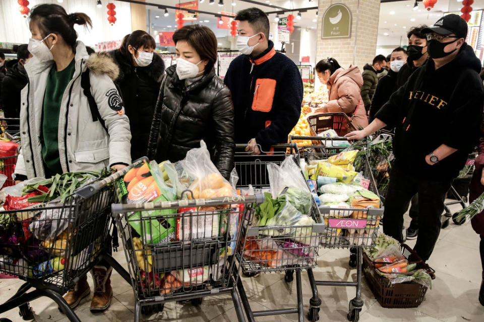 Pictured are several shoppers wearing masks with trolleys full of food at a Wuhan supermarket.