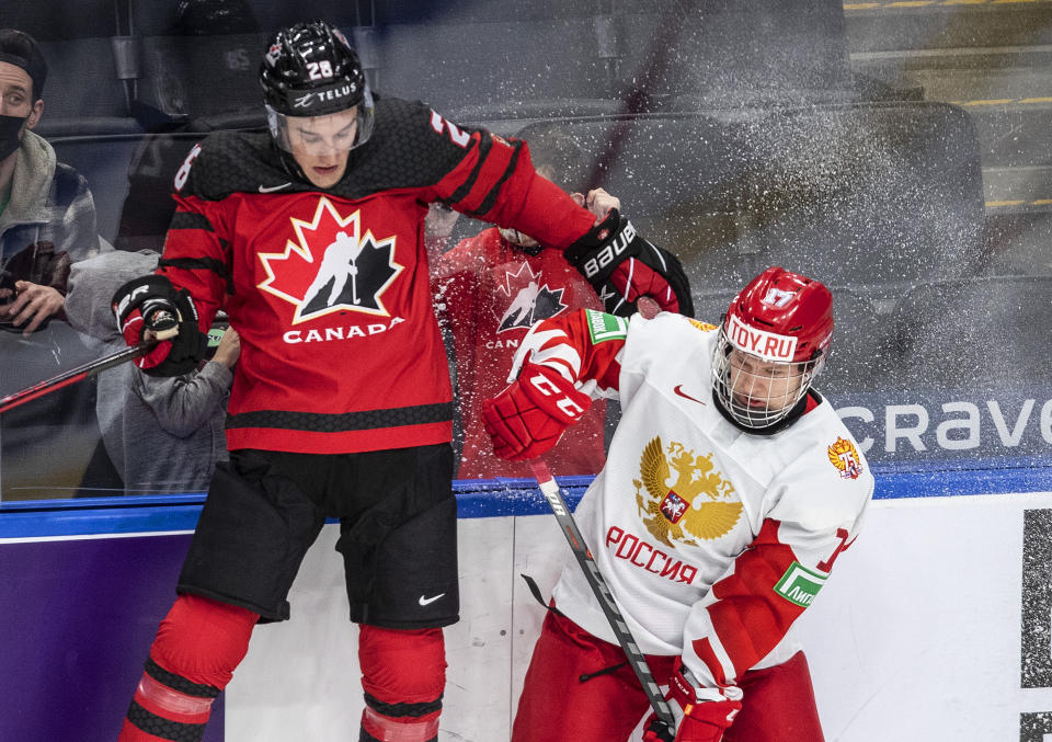 FILE - Canada's Ryan O'Rourke (28) is checked by Russia's Matvei Michkov (17) during the first period of an IIHF world junior hockey championships exhibition game in Edmonton, Alberta, Thursday, Dec. 23, 2021. Michkov might be the best prospect out of Russia in nearly a decade. He might be the best since Alex Ovechkin and Evgeni Malkin in 2005. But Michkov still is no lock to get drafted in the top five because he’s still under contract in the KHL for three more seasons. That's giving NHL teams reason to worry he might never make it to North America. (Jason Franson/The Canadian Press via AP, File)