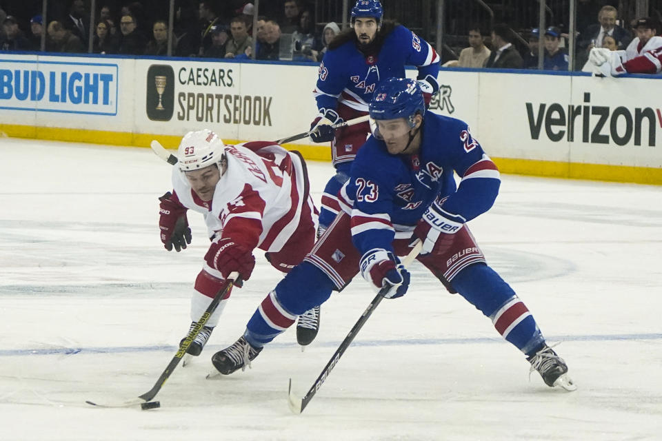 Detroit Red Wings' Alex DeBrincat, left, and New York Rangers' Adam Fox (23) battle for a loose puck during the first period of an NHL hockey game, Wednesday, Nov. 29, 2023, in New York. (AP Photo/Bebeto Matthews)