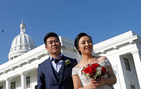 A Chinese wedding couple poses for photographs during a mass wedding ceremony for fifty Chinese couples in Colombo, Sri Lanka December 17, 2017. REUTERS/Dinuka Liyanawatte