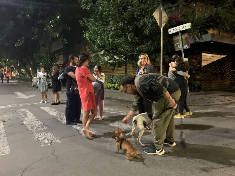 People wait outside their homes after a tremor was felt in Mexico City