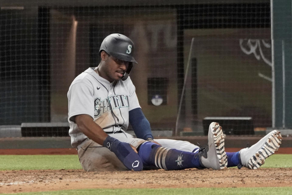 Seattle Mariners baserunner Kyle Lewis sits at home plate after being tagged out to end a baseball game in the ninth inning against the Texas Rangers, Saturday, May 8, 2021, in Arlington, Texas. (AP Photo/Louis DeLuca)