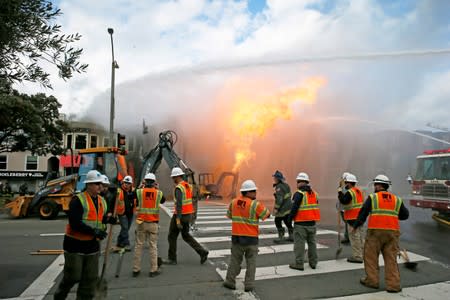 FILE PHOTO: PG&E officials are seen as firefighters battle a fire following an explosion at Geary boulevard and Parker Avenue in San Francisco