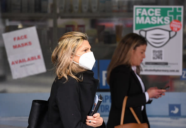 People wearing face masks walk past a sign advertising masks in Melbourne.