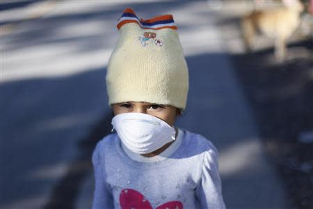 A girl covers her face with a mask for protection from the ashes spewed by the Chaparrastique volcano in the municipality of San Miguel December 30, 2013. REUTERS/Ulises Rodriguez