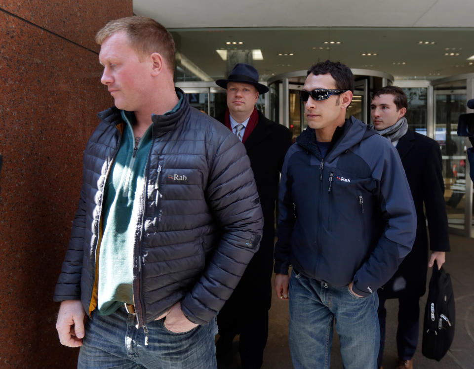 James Brady, and Andrew Rossig, foreground left and right, two parachutists who jumped from One World Trader Center in September 2013, are accompanied by attorneys Timothy Parlatore, background left and Andrew Mancilla, to surrender to police, in New York, Monday, March 24, 2014. Monday's arrests come eight days after a 16-year-old was arrested on charges of climbing up to the top of the nation's biggest skyscraper. Police had no immediate information on Monday's arrests. They had said they were looking for two parachutists seen floating near the building Sept. 30. The defense attorneys say three accused jumpers and an alleged accomplice on the ground are expecting to face felony burglary charges. The attorneys say the defendants are experienced BASE jumpers, the acronym stands for "building, span, antenna, earth." The lawyers say the men took care to keep from endangering anyone. (AP Photo/Richard Drew)