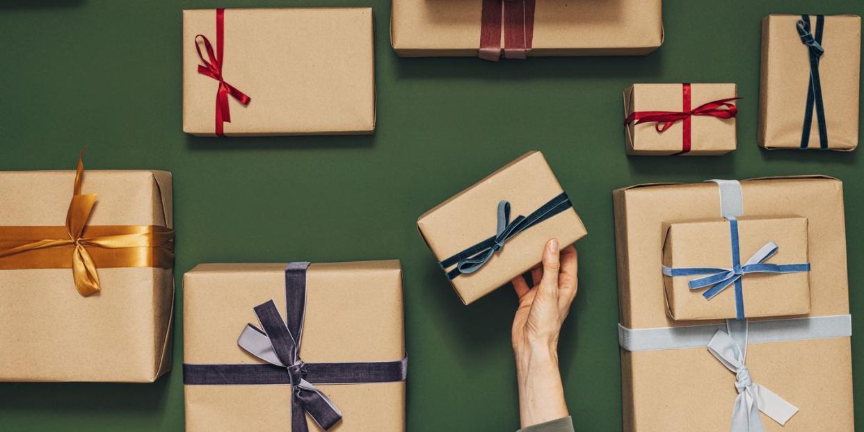 anonymous person holding one of many gift boxes on a green background