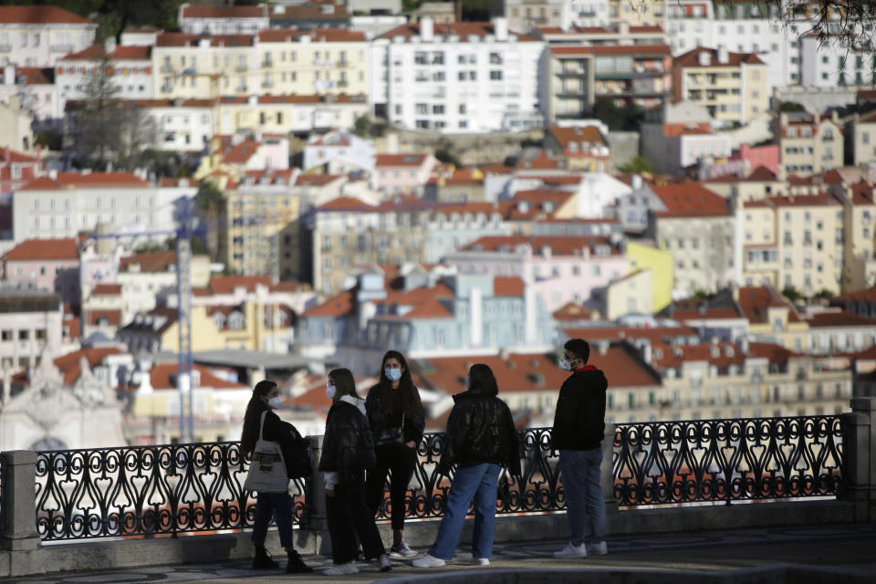 FILE - In this March 11, 2021 file photo, a group of young people wearing face masks chat at a viewpoint overlooking Lisbon's old center. Travel in and out of the Lisbon metropolitan area is to be banned over coming weekends as Portuguese authorities respond to a spike in new COVID-19 cases in the region around the capital, officials announced Thursday, June 17. (AP Photo/Armando Franca)