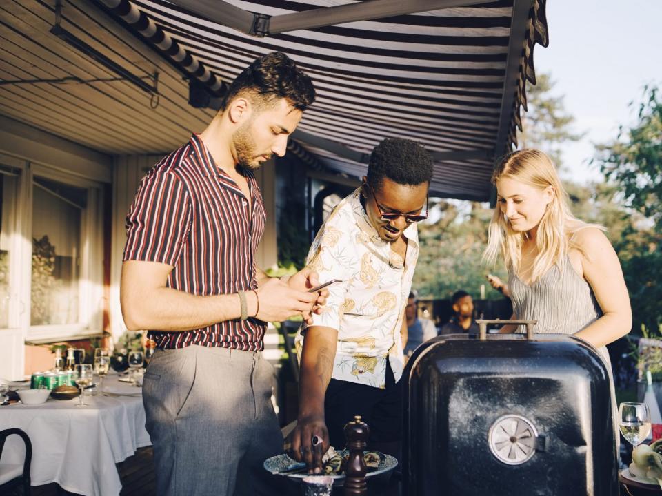 backyard-party: 3 friends standing around a grill