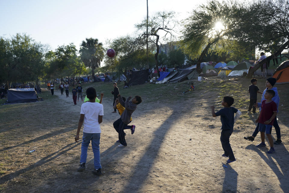Venezuelan migrants play soccer at a makeshift camp alongside a river bank in Matamoros, Mexico, Thursday, Dec. 22, 2022. (AP Photo/Fernando Llano)