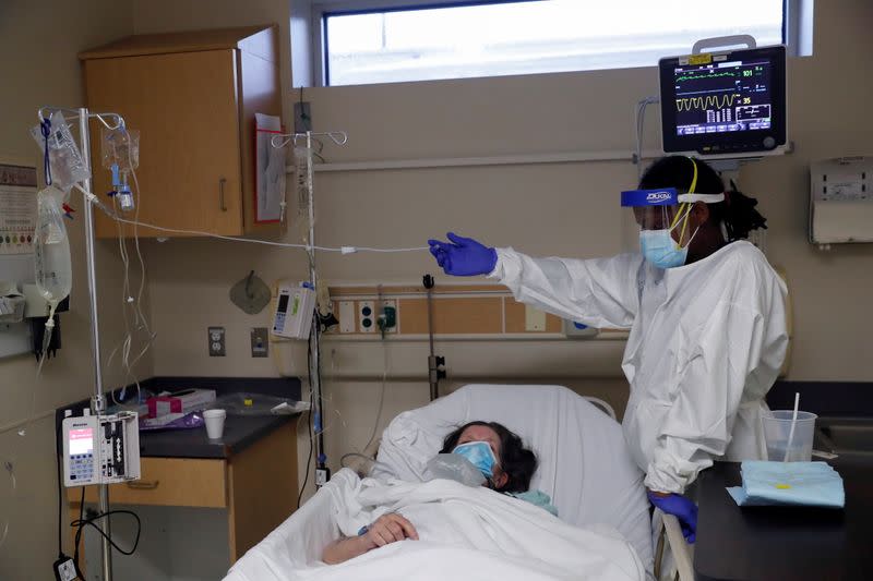 Patient Care Technician Fanta Keita treats Donna Plummer, a coronavirus disease (COVID-19) positive patient, as she lays on an emergency room bed at Roseland Community Hospital on the South Side of Chicago, Illinois