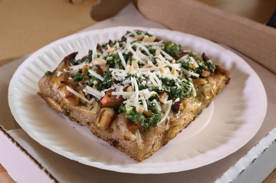 A slice of a seasonal pizza featuring roasted local mushrooms, arugula, pine nuts and herb pesto at Wildflour on North Winton Road in Rochester Friday, Aug. 11, 2023.