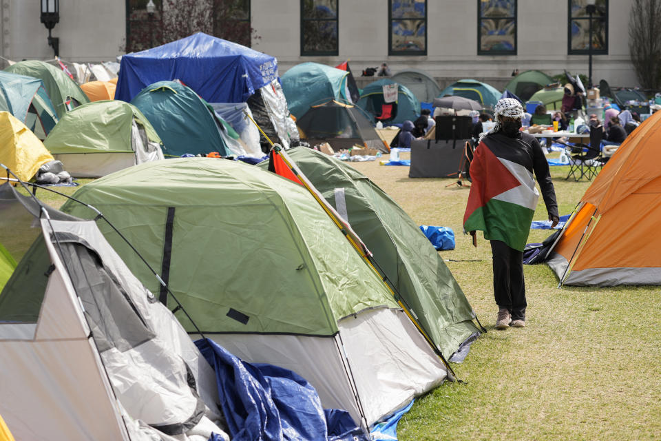 Student stands near dozens of tents near a building.