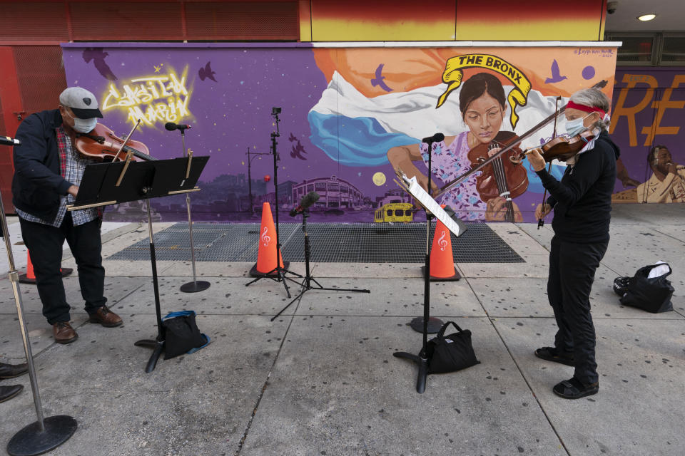 Miembros del NY Phil Bandwagon, la violinista Fiona Simon, a la derecha, y el músico de viola Robert Rinehart, a la izquierda, actúan ante el Centro de Educación y Arte Casita Maria en Hunts Point, en el Bronx, Nueva York, el viernes 2 de octubre de 2020. El equipo hizo tres conciertos no anunciados en rincones de la ciudad de Nueva York entre el viernes y el domingo, ofreciendo música de cámara dentro de las actividades de otoño de la orquesta. (AP Foto/Mary Altaffer)