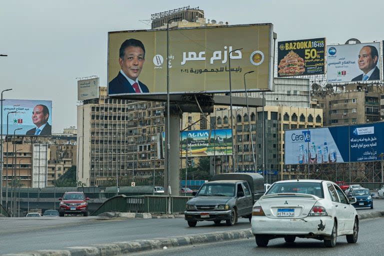 Los automovilistas pasan junto a carteles de campaña del presidente de Egipto, Abdel Fattah al-Sisi, y del candidato presidencial Hazem Omar, del Partido Republicano del Pueblo (C), a lo largo de una calle de El Cairo el 7 de diciembre de 2023, antes de las elecciones presidenciales del país.