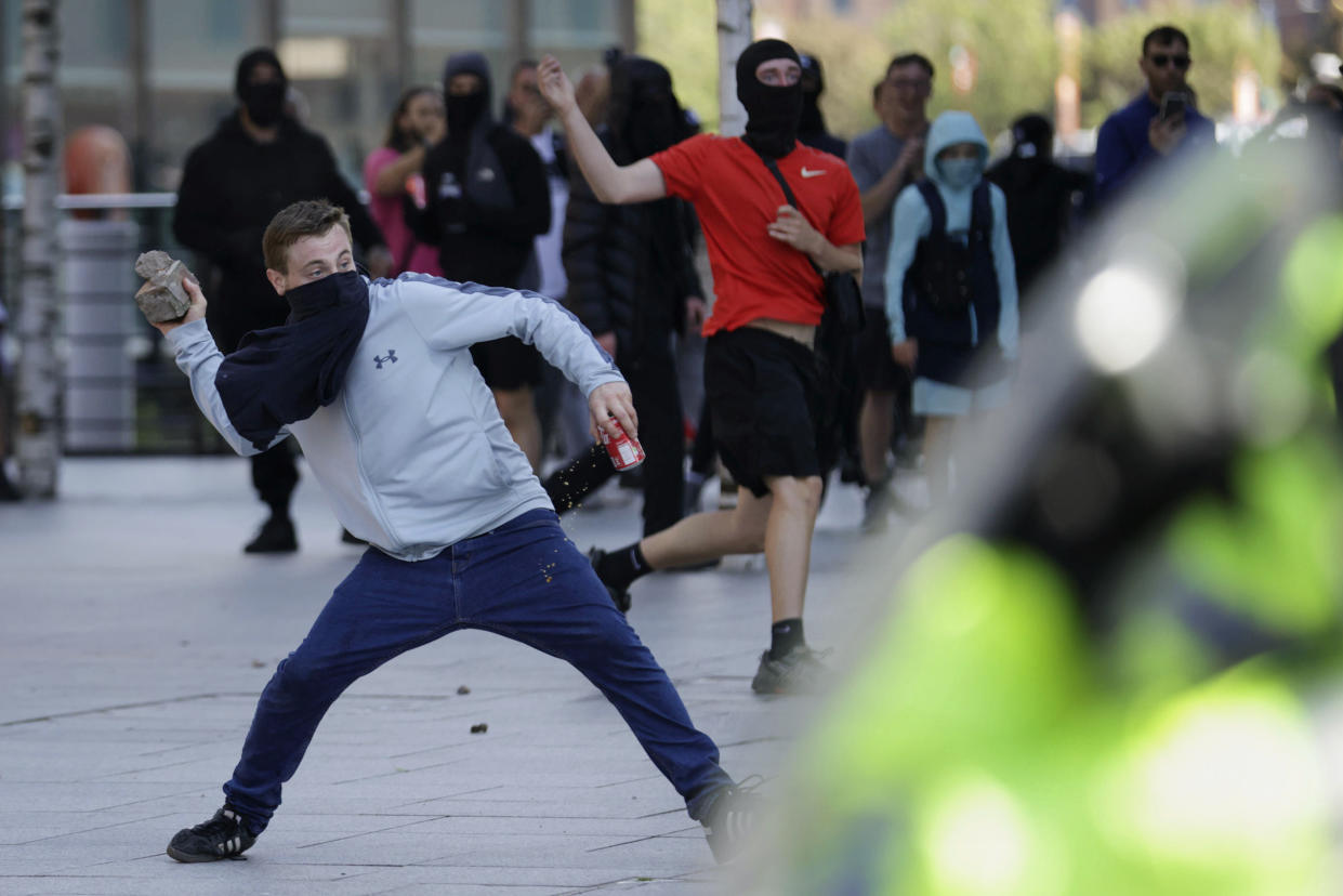 A demonstrator throws a brick during a protest in Liverpool