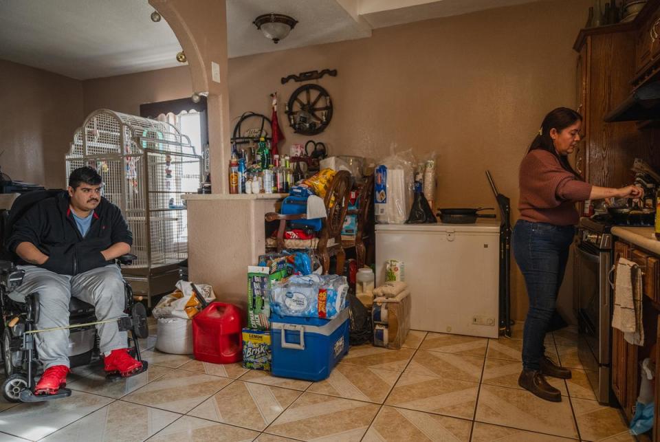 Juvencia Padilla (right) cooking dinner. She raises her two sons by herself while being a caregiver to her son, Tino (left), who is paralyzed from the waist down.  Fort Hancock, Texas. November 28, 2023.