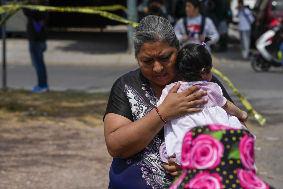 FILE - A resident cradles an infant as she walks past a crime scene where a passenger was shot dead inside a bus, in Celaya, Mexico, Feb. 29, 2024. As Mexico's June 2 presidential election approaches, this city lies at the crossroads of a national debate about security policy. (AP Photo/Fernando Llano, File)