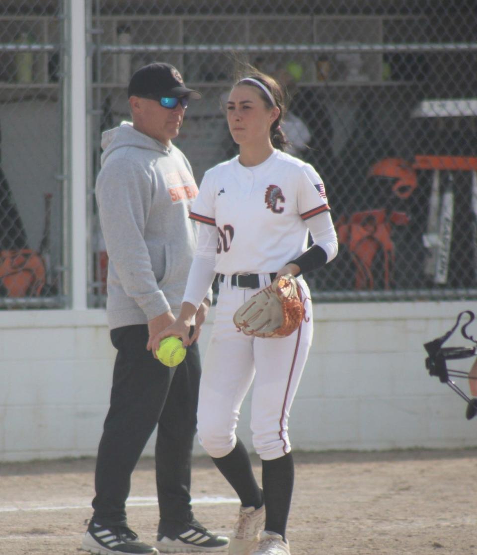 Cheboygan senior Libby VanFleet walks out to pitch while father and assistant coach Mike VanFleet looks on.