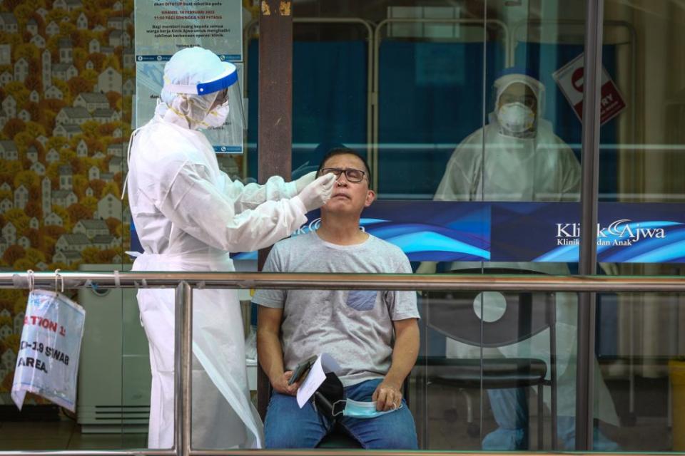 A health worker in protective suit collects swab samples from a motorist at a drive-through testing site for Covid-19 at Ajwa Clinic in Shah Alam February 9, 2022. — Picture by Yusof Mat Isa