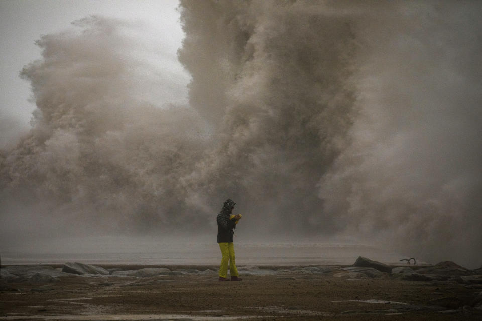 A woman photographs the Mediterranean sea as the waves hit the breakwater during a storm in Barcelona, Spain, Tuesday, Jan. 21, 2020. A winter storm lashed much of Spain for a third day Tuesday, leaving 200,000 people without electricity, schools closed and roads blocked by snow as it killed four people. Massive waves and gale-force winds smashed into seafront towns, damaging many shops and restaurants. (AP Photo/Emilio Morenatti)