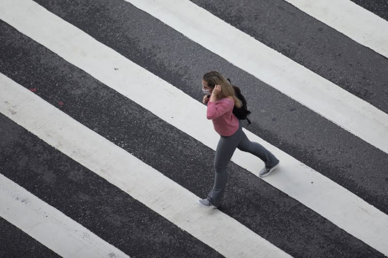 A woman wearing a face mask crosses a street amid the coronavirus disease (COVID-19) outbreak in Sao Paulo