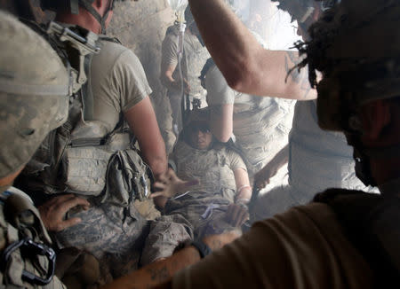 FILE PHOTO: A U.S. soldier, wounded by sniper fire, is evacuated by his comrades in the village of Bargematal, Nuristan province, August 25, 2009. REUTERS/Oleg Popov