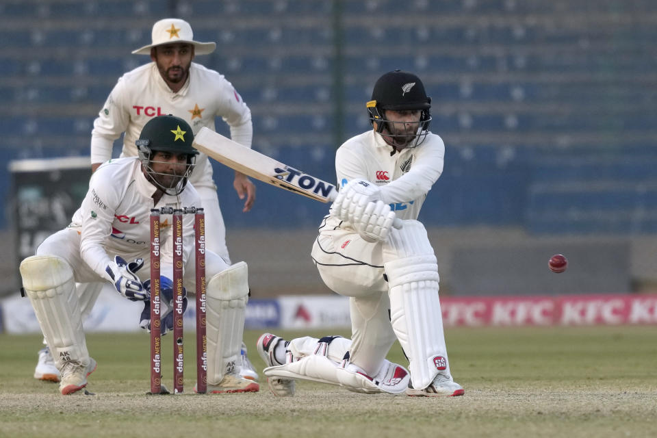 New Zealand's Devon Conway, right, plays reverse sweep as Pakistan's Sarfraz Ahmed, center front, and Agha Salman watch during the fifth day of first test cricket match between Pakistan and New Zealand, in Karachi, Pakistan, Friday, Dec. 30, 2022. (AP Photo/Fareed Khan)