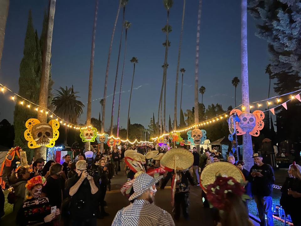 The crowd walks down one of the main thoroughfares just after sunset during the Día de Los Muertos celebration at the Hollywood Forever Cemetery in Los Angeles on Saturday, Oct. 28, 2023.