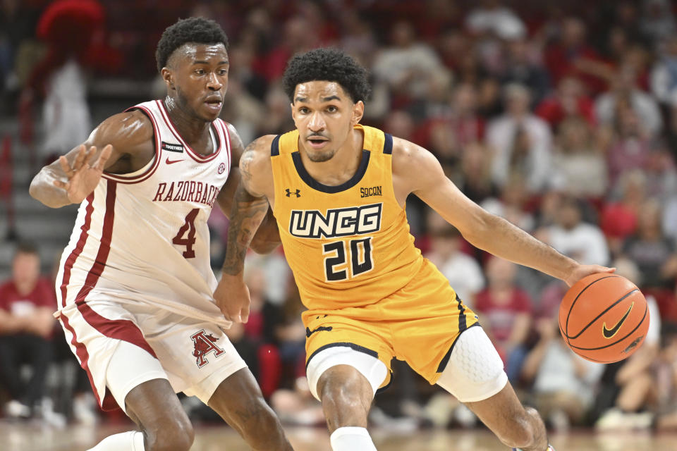 UNC Greensboro guard Joryam Saizonou (20) tries to drive past Arkansas guard Davonte Davis (4) during the first half of an NCAA college basketball game Friday, Nov. 17, 2023, in Fayetteville, Ark. (AP Photo/Michael Woods)