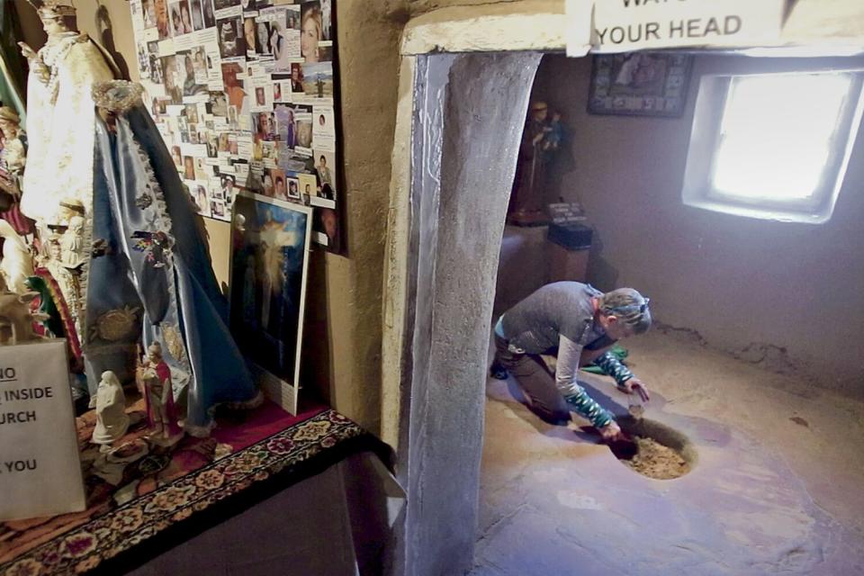 A pilgrim scoops holy dirt from the Santuario de Chimayo