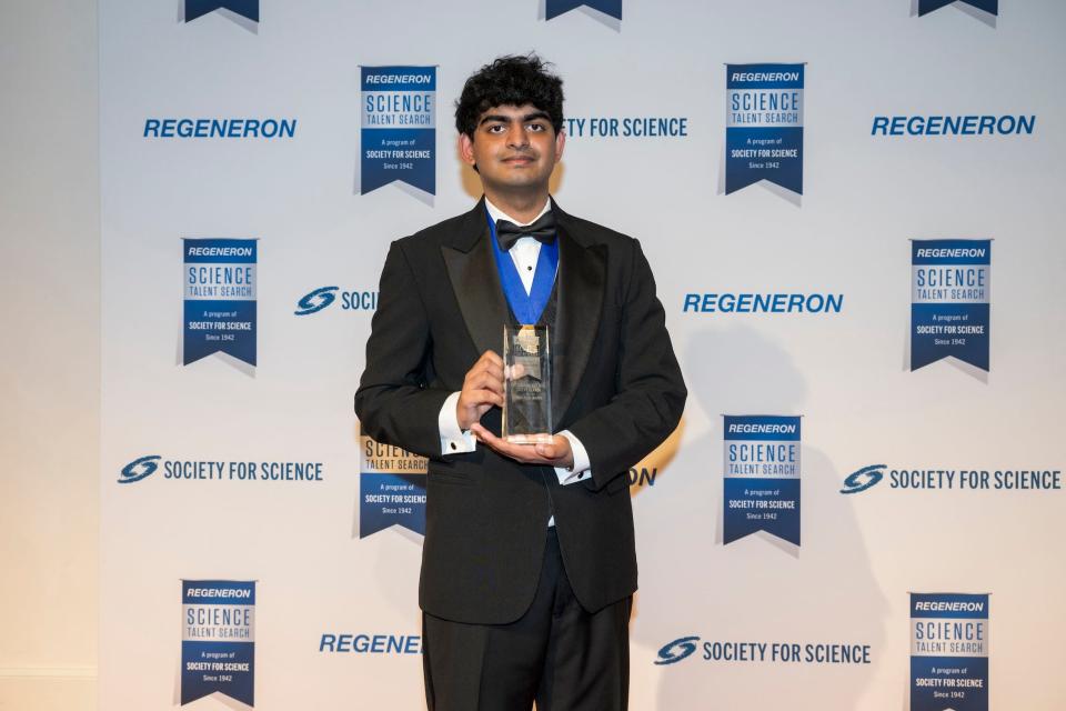 Achyuta Rajaram, wearing a tux, holds his first-prize glass plaque for the Regeneron Science Talent Search