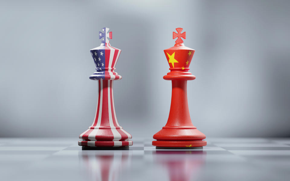 Two king chess pieces textured with American and Chinese flags on black and white chessboard. Politics and checkmate concept. Horizontal composition with selective focus and copy space.