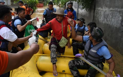 Rescuers evacuate residents during heavy flooding in Cagayan de Oro city in the Philippines - Credit: Froilan Gallardo/Reuters