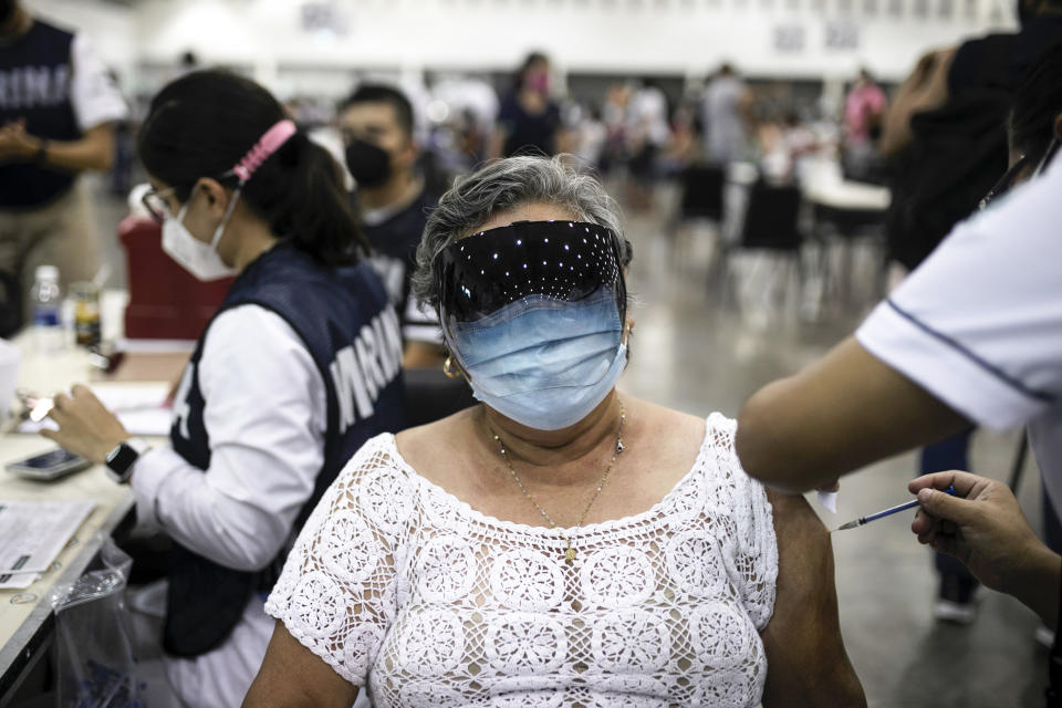 A Navy health worker inoculates a woman with the single-dose CanSino COVID-19 vaccine, during a vaccination drive for education workers at the World Trade Center in Boca del Rio, Veracruz state, Mexico, Tuesday, April 20, 2021. The Mexican government began giving teachers in five other states the single-dose CanSino COVID-19 vaccine to speed up their return to the classroom before the end of the school year in July. (AP Photo/Felix Marquez)