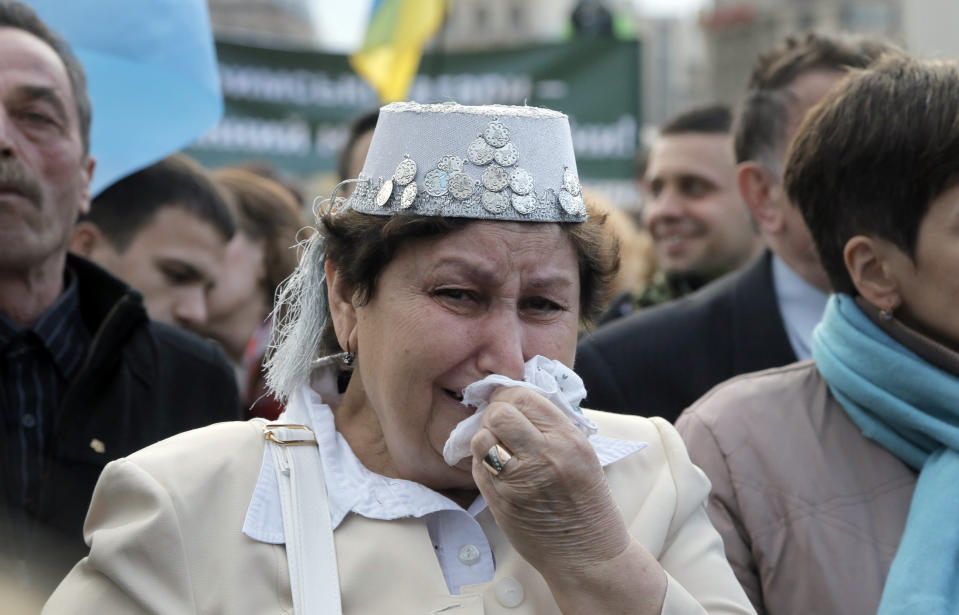 FILE - In this May 18, 2016 file photo, a Crimean Tatar woman in a national costume wipes away her tears at a rally to mark the 72nd anniversary of the deportation of Crimean Tatars in Kyiv, Ukraine, Wednesday, May 18, 2016. The fate of Crimean Tatars is one of the top issues at the inaugural meeting of the Crimean Platform on Monday Aug. 23, 2021, an international summit called by Ukraine to build up pressure on Russia over the annexation that has been denounced as illegal by most of the world. (AP Photo/Efrem Lukatsky, File)