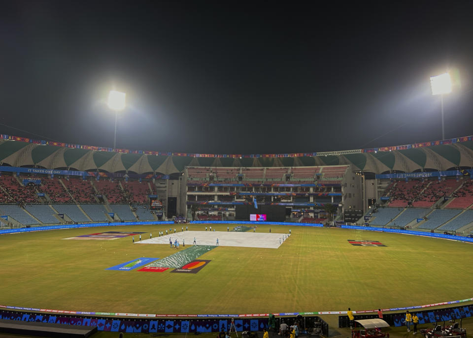 Grounds men cover the pitch following rains and strong winds during the ICC Men's Cricket World Cup match between Australia and Sri Lanka in Lucknow, India, Monday, Oct. 16, 2023. (AP Photo/Aijaz Rahi)