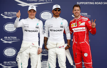 Formula One - F1 - Australian Grand Prix - Melbourne, Australia - 25/03/2017 - Mercedes driver Lewis Hamilton (C) of Britain reacts after setting pole position in qualifying alongside team mate Valtteri Bottas (L) of Finland and Ferrari's Sebastian Vettel of Germany. REUTERS/Brandon Malone