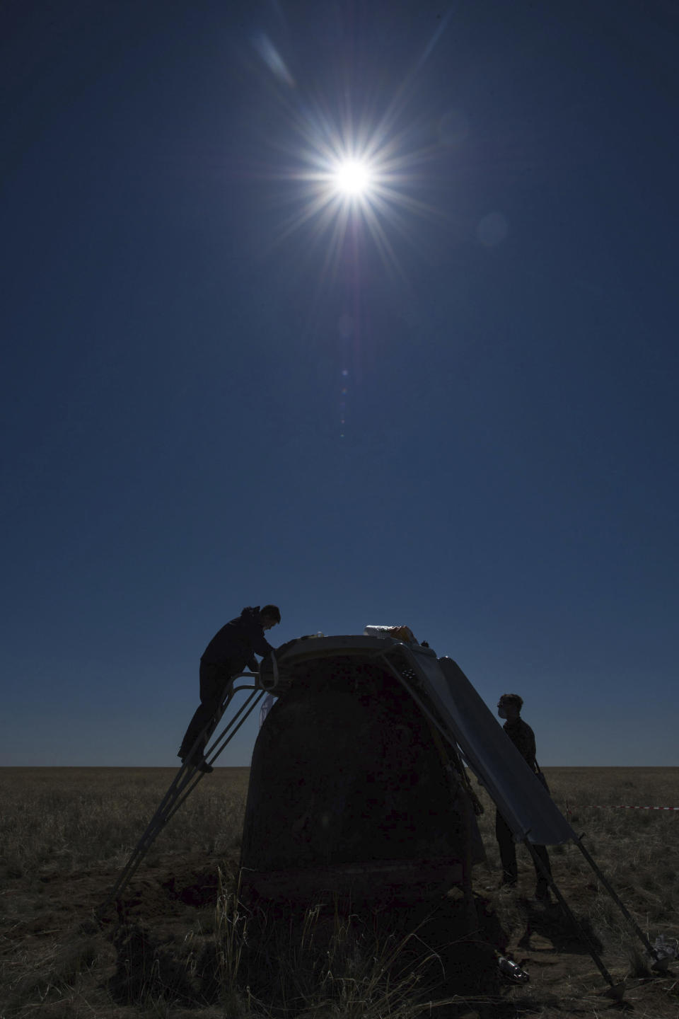 In this handout photo released by Gagarin Cosmonaut Training Centre (GCTC), Roscosmos space agency, specialists work after the landing of the Russian Soyuz MS-15 space capsule near Kazakh town of Dzhezkazgan, Kazakhstan, Friday, April 17, 2020. An International Space Station crew has landed safely after more than 200 days in space. The Soyuz capsule carrying NASA astronauts Andrew Morgan, Jessica Meir and Russian space agency Roscosmos' Oleg Skripochka touched down on Friday on the steppes of Kazakhstan. (Andrey Shelepin, Gagarin Cosmonaut Training Centre (GCTC), Roscosmos space agency, via AP)