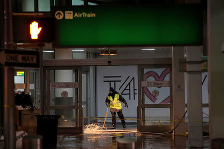 A worker attempts to remove water following a water main break in the arrivals area of Terminal 4 at John F. Kennedy International Airport in New York City, U.S. January 7, 2018. REUTERS/Andrew Kelly