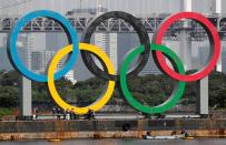 Workers prepare to carry the giant Olympic rings, which are being temporarily removed for maintenance, at the waterfront area at Odaiba Marine Park in Tokyo