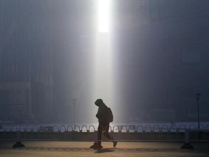 A pedestrian walks past a beam of sunlight cast through two buildings amid heavy smog in Shenyang, Liaoning province December 26, 2014.  REUTERS/Stringer