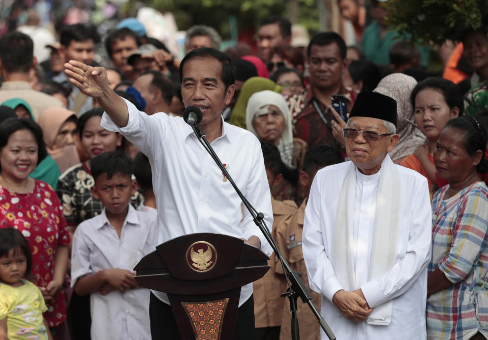 Indonesian President Joko Widodo, left, gestures while his running mate Ma'ruf Amin listens during a speech declaring their victory in the country's presidential election, at a slum in Jakarta, Indonesia, Monday, Tuesday, May 21, 2019. Indonesia's President Joko Widodo has been elected for a second term, official results showed Tuesday, in a victory over a would-be strongman who aligned himself with Islamic hardliners. (AP Photo/Dita Alangkara)