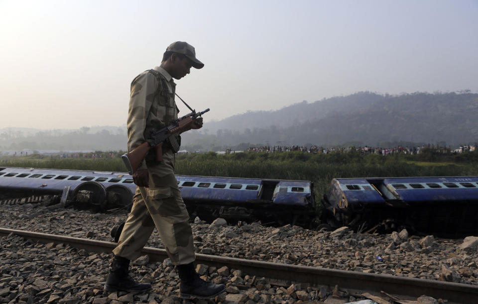 A security officer patrols past a train that derailed near Jagiroad Railway Station, about 90 kilometers (56 miles) east of Gauhati, India, Wednesday, April 16, 2014. According to a Northeast Frontier Railway officer, dozens of people were injured when the train jumped the tracks and derailed early Wednesday. (AP Photo/Anupam Nath)