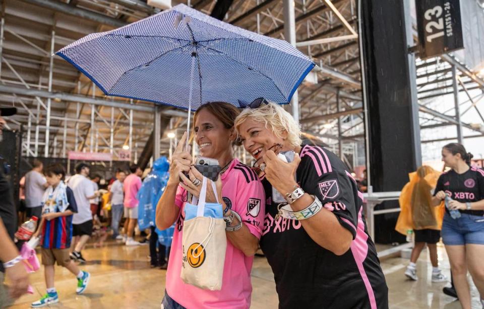 Andrea Monzani, left, and Emma Morales try to stay dry during a weather delay before the start of Inter Miami’s The Unveil at DRV PNK Stadium on Sunday, July 16, 2023, in Fort Lauderdale, Fla. The event was held to officially welcome Argentine forward Lionel Messi and Spanish midfielder Sergio Busquets to the team. MATIAS J. OCNER/mocner@miamiherald.com