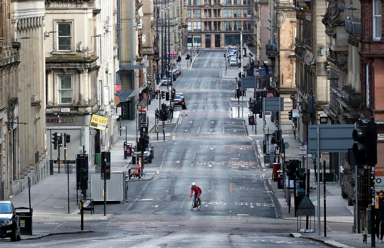 A cyclist makes his way up a quiet Saint Vincent Street in Glasgow: PA