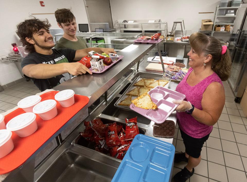 Julie Friedrichsen, Perry High School head cook, hands a tray of pizza to Mason Mayle, as Brayden Miller waits in line at Perry High School's summer meal program. Perry Local Schools is offering free breakfast and free lunch to any child ages 18 and younger as part of Ohio's Summer Food Service Program.
