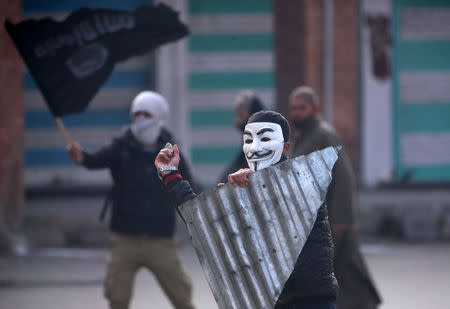 A demonstrator wearing a Guy Fawkes mask throws a stone towards the Indian police (not pictured) during a protest after Friday prayers, in Srinagar December 14, 2018. REUTERS/Danish Ismail/File Photo