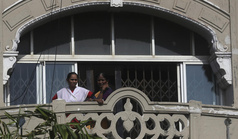 Neighbors watch as an ambulance carrying the body of Bollywood actor Sushant Singh Rajput leaves from the building he lived in Mumbai, India, Sunday, June 14, 2020. Rajput was found dead at his Mumbai residence on Sunday, police and Indian media reports said. (AP Photo/Rafiq Maqbool)